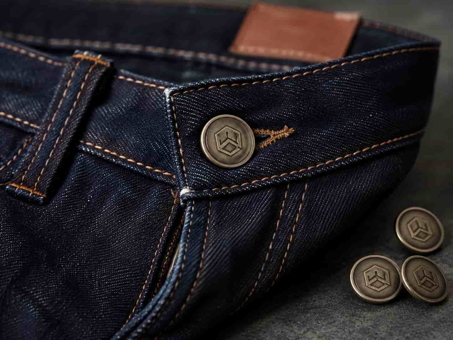 jense button，Custom jeans button with clear logo and premium finish on dark denim waistband